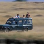 Africa, Kenya, Masai Mara Game Reserve, Blurred image of tourists in safari truck during game drive on savanna