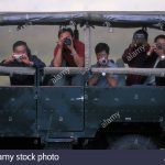 Africa, Kenya, Masai Mara Game Reserve, Asian tourists pointing cameras from safari truck on game drive